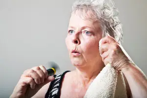 _Woman experiencing a hot flush, fanning herself with visible discomfort — representing common perimenopause symptoms and hormonal shifts.