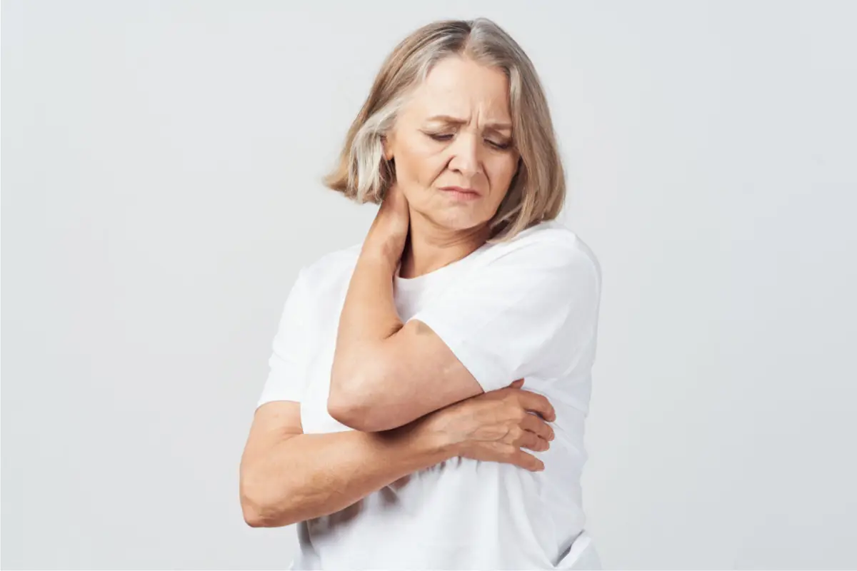 Joint Pain at Menopause Midlife woman gently holding her neck in discomfort, symbolizing joint or muscle pain during menopause.