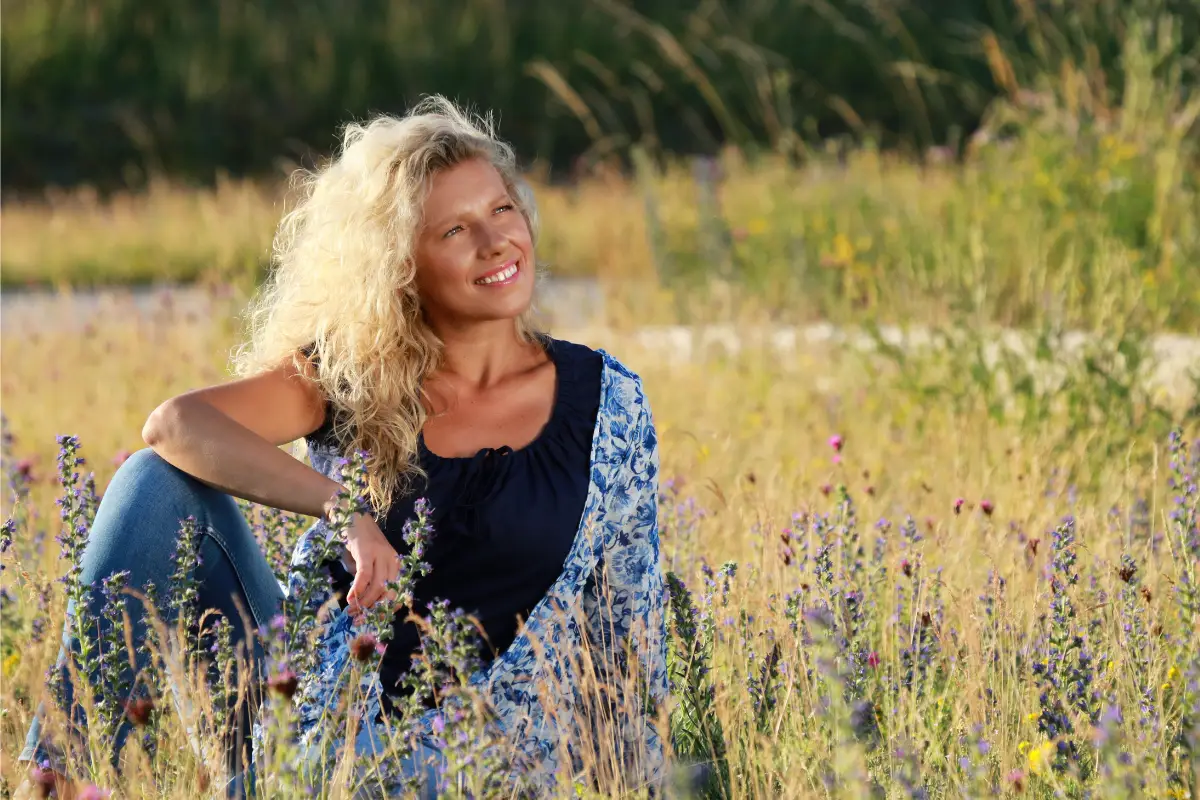 Woman sitting peacefully in a sunlit lavender field, symbolizing natural healing, hormonal balance, and gentle menopause support.